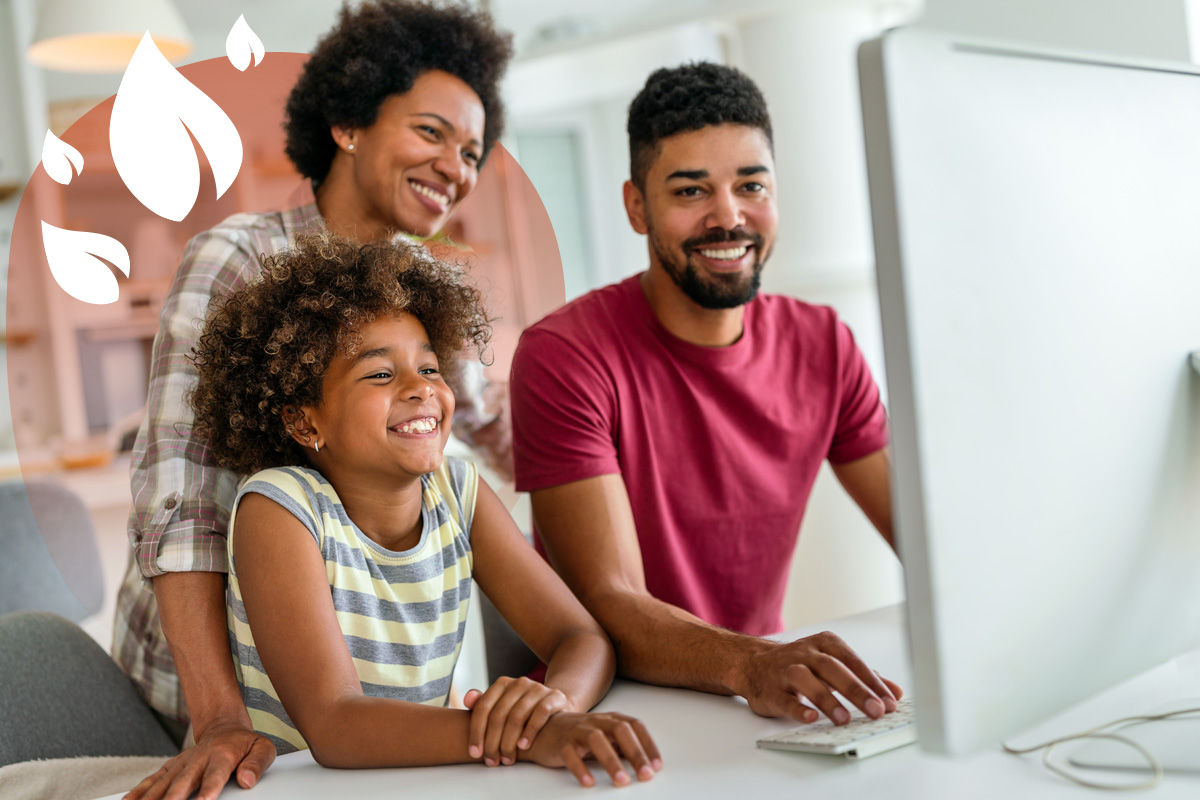 Smiling parents and child at home using a desktop computer for learning