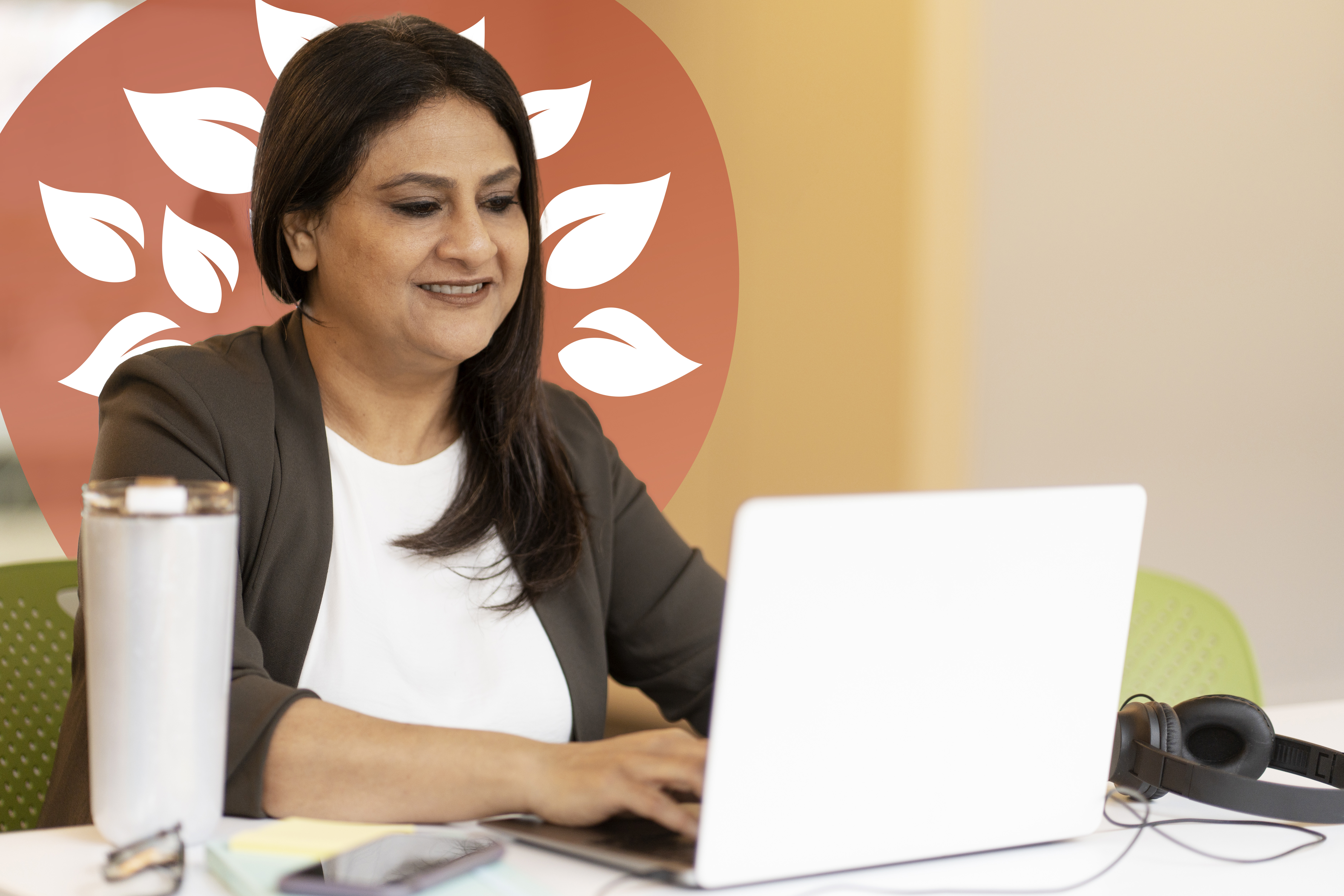 A female tutor sits at a desk, focused on her work while using a laptop computer.