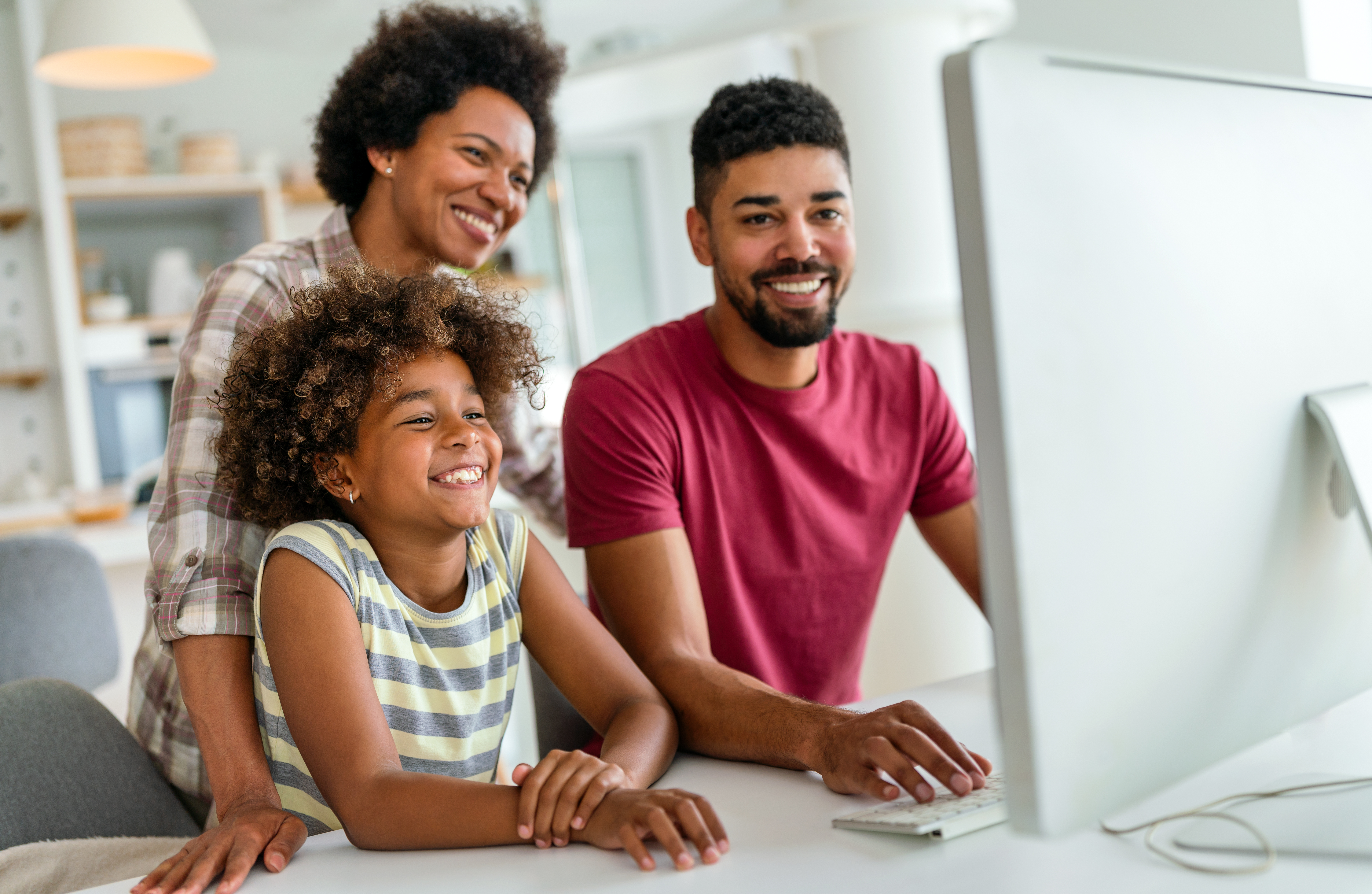Smiling parents and child at home using a desktop computer for learning