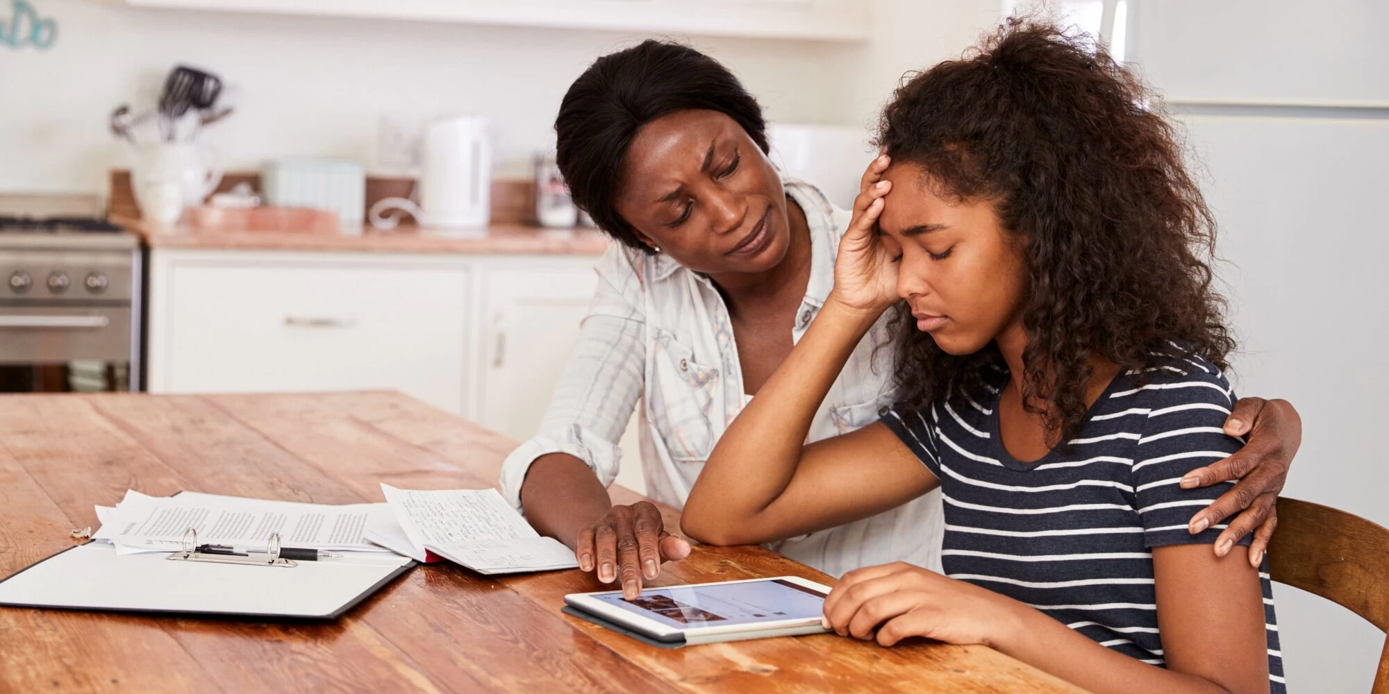 Mother helping teenage daughter with her studies, whilst she faces a moment of distress from anxiety. 