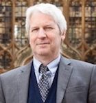 A close-up photograph of Lee Wilcock, who joined Wolsey Hall Oxford as Principal in 2009. Lee has short white hair and is wearing a suit. He is looking at the camera.