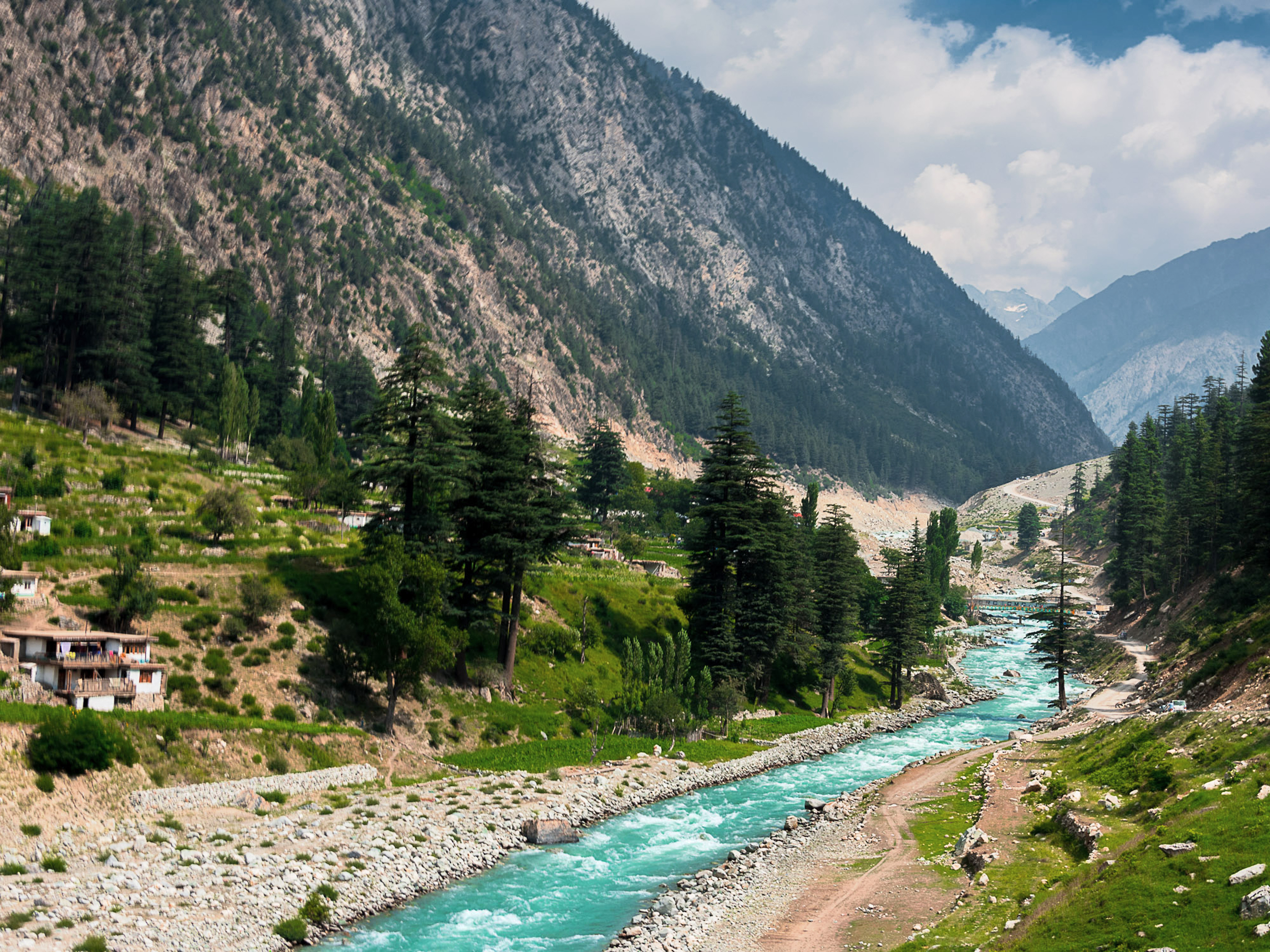 Lush green valley and turquoise river flowing through the mountains of northern Pakistan