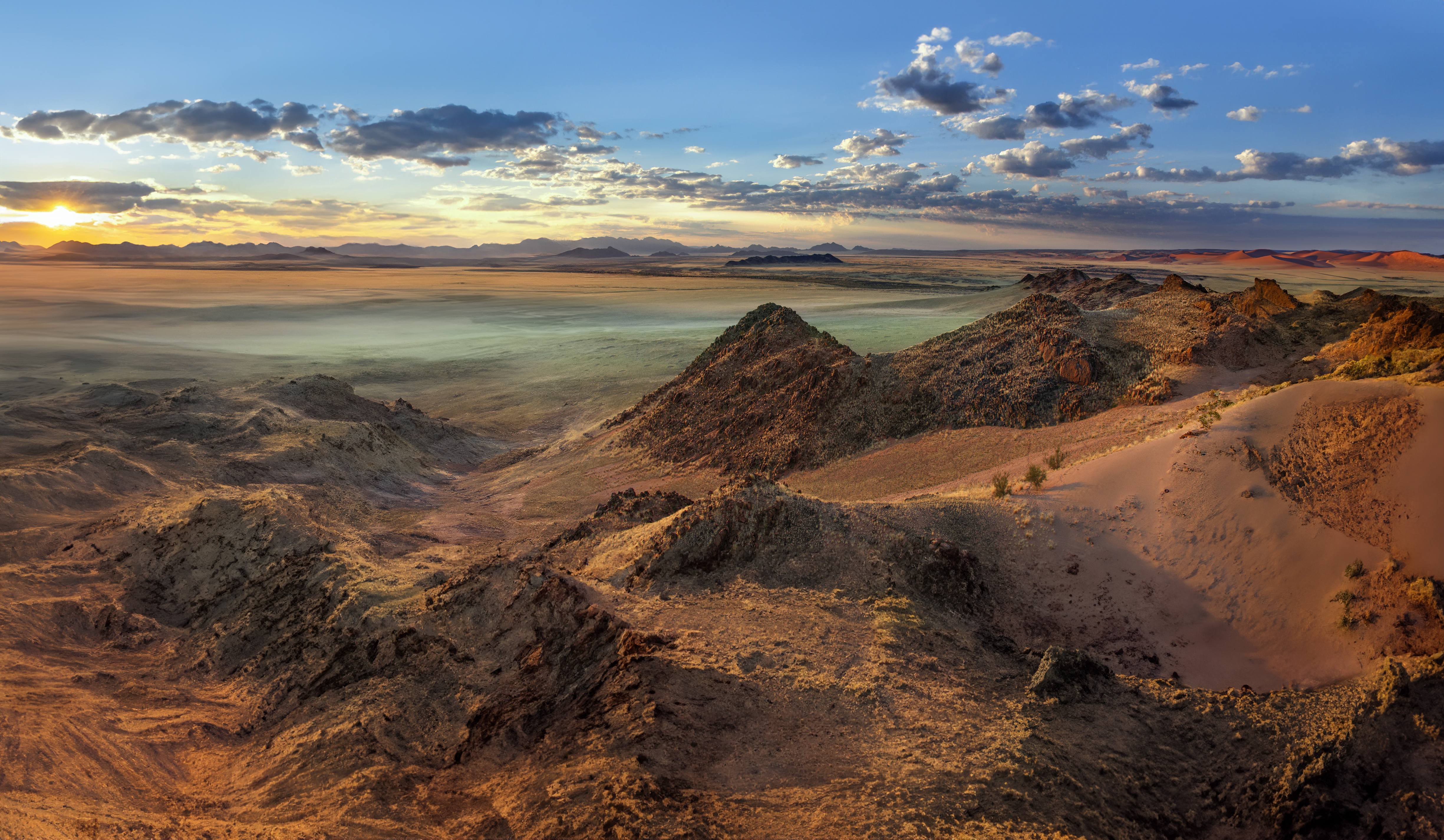 Expansive desert landscape in Namibia at sunset with rocky ridges and open plains