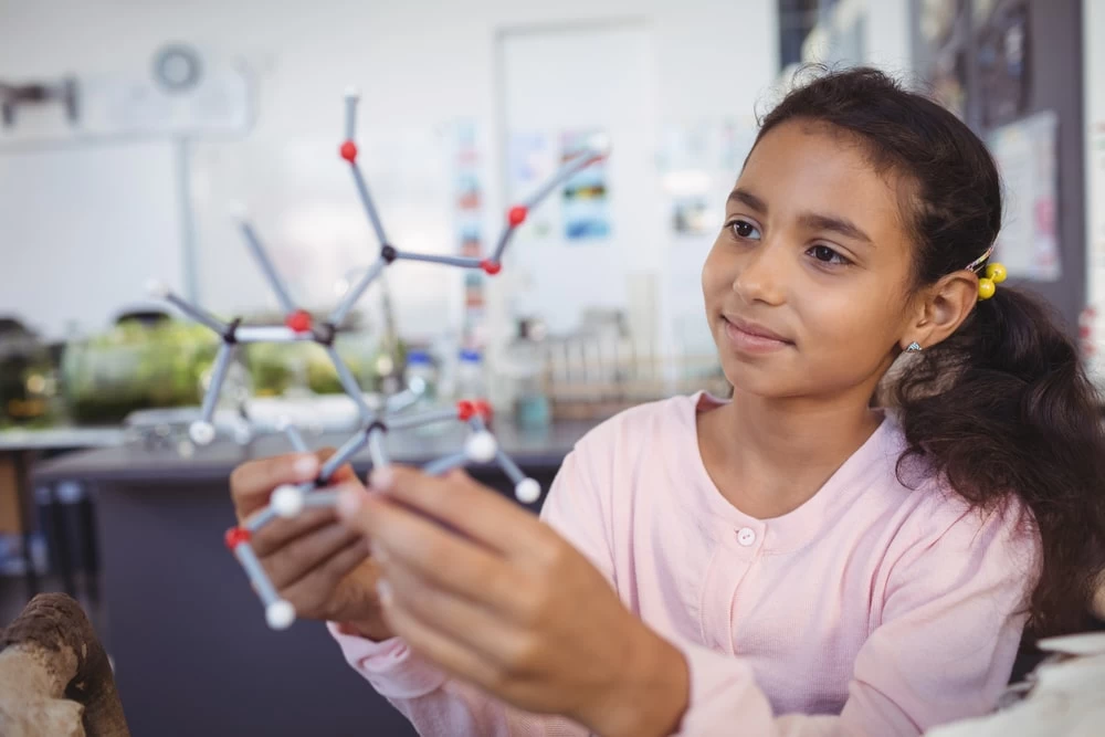 A young student observing a molecular structure model. 