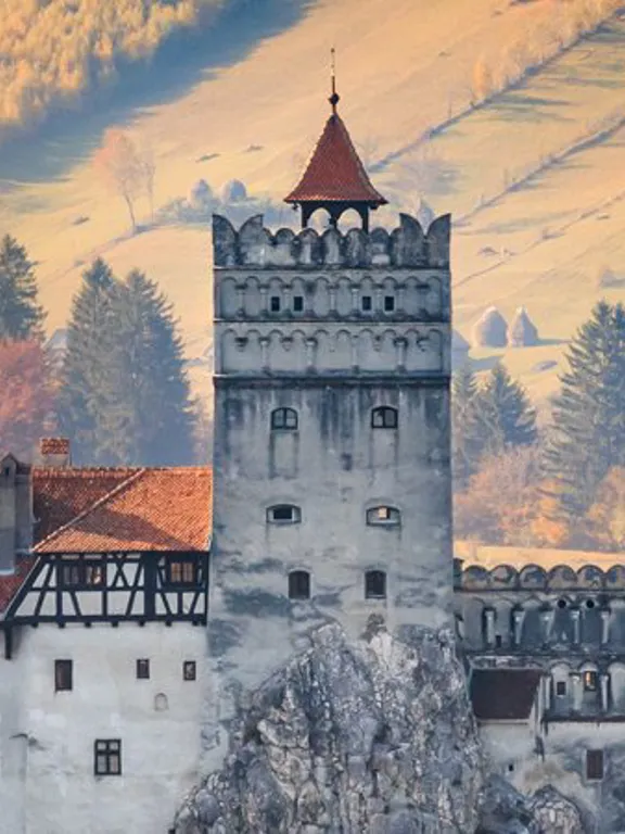 A landscape view of a Romanian castle in the middle of the country side.