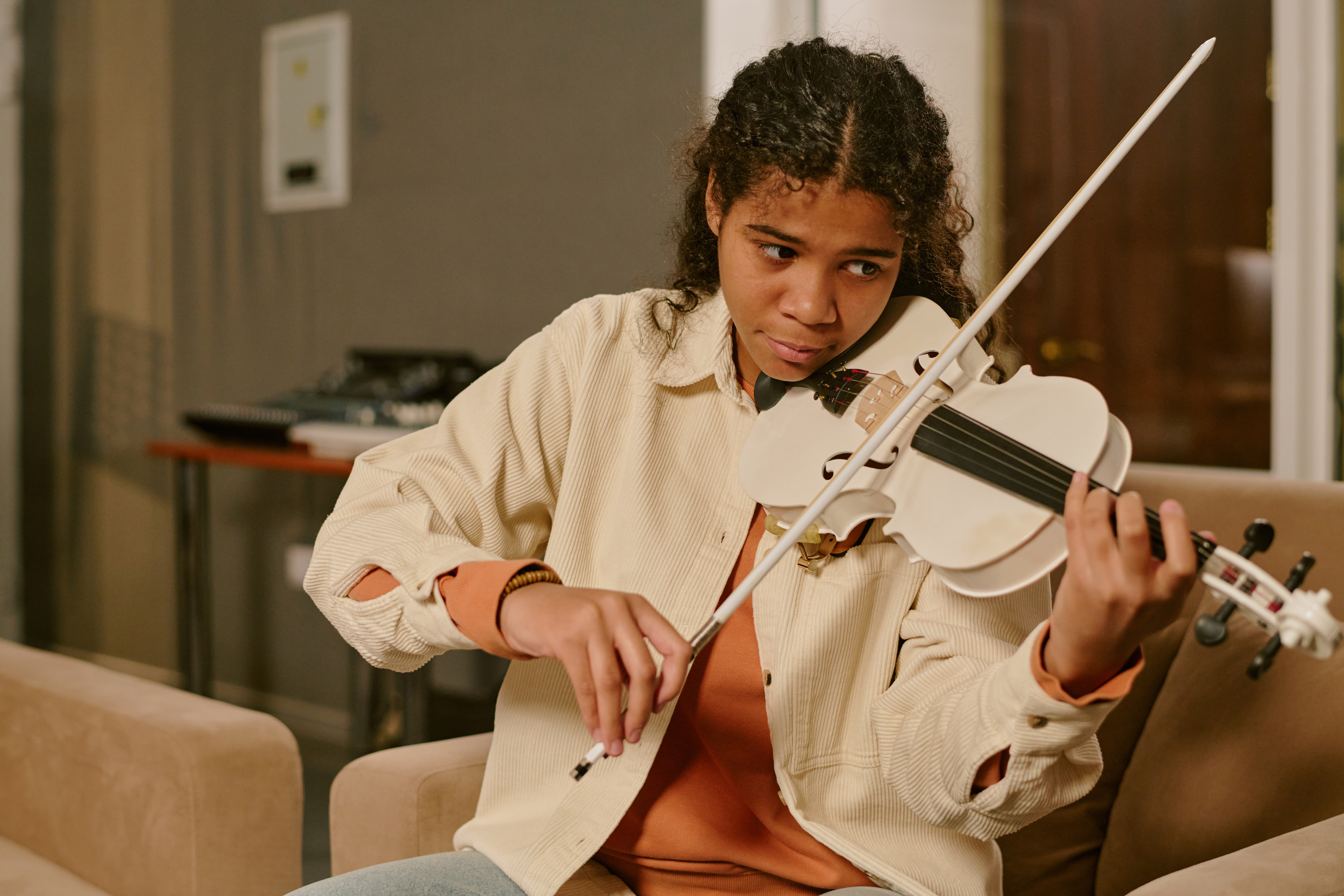 Focused teen practising the violin in a warm indoor space