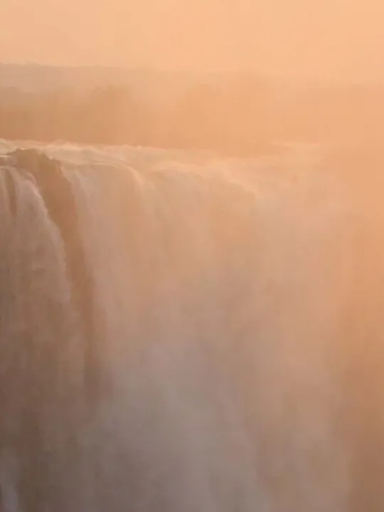 Victoria Falls in Zimbabwe with mist rising at sunset.