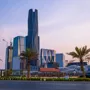 Modern skyscrapers in Riyadh, Saudi Arabia, seen from a palm-lined boulevard at sunset