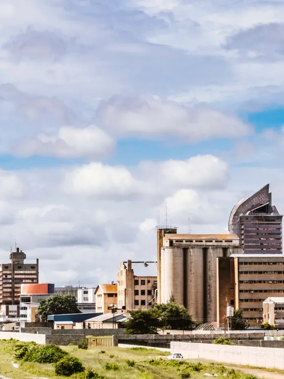 City skyline of Lusaka, Zambia under a cloudy sky with modern and traditional architecture.