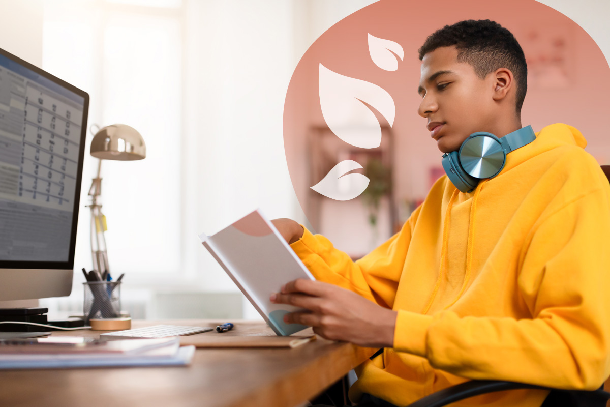 A focused teenage student works at his desk with a schedule on his computer screen, illustrating one of the key benefits of structured homeschooling: a personalised and organised learning environment.