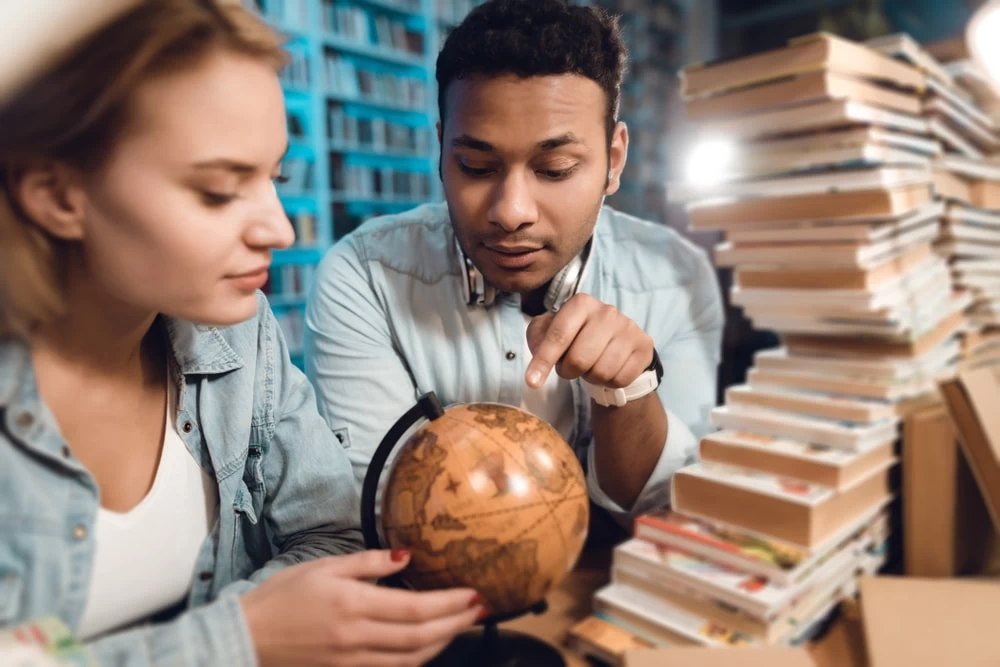 A Level students looking at a globe for their Geography studies. 