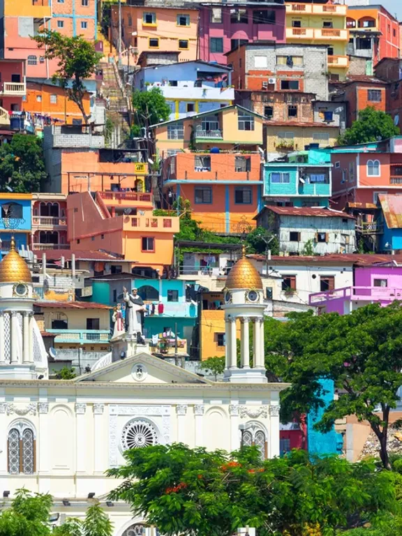 A landscape view of an Ecuadorian city, with a church in the forefront, and colourful buildings in the background.