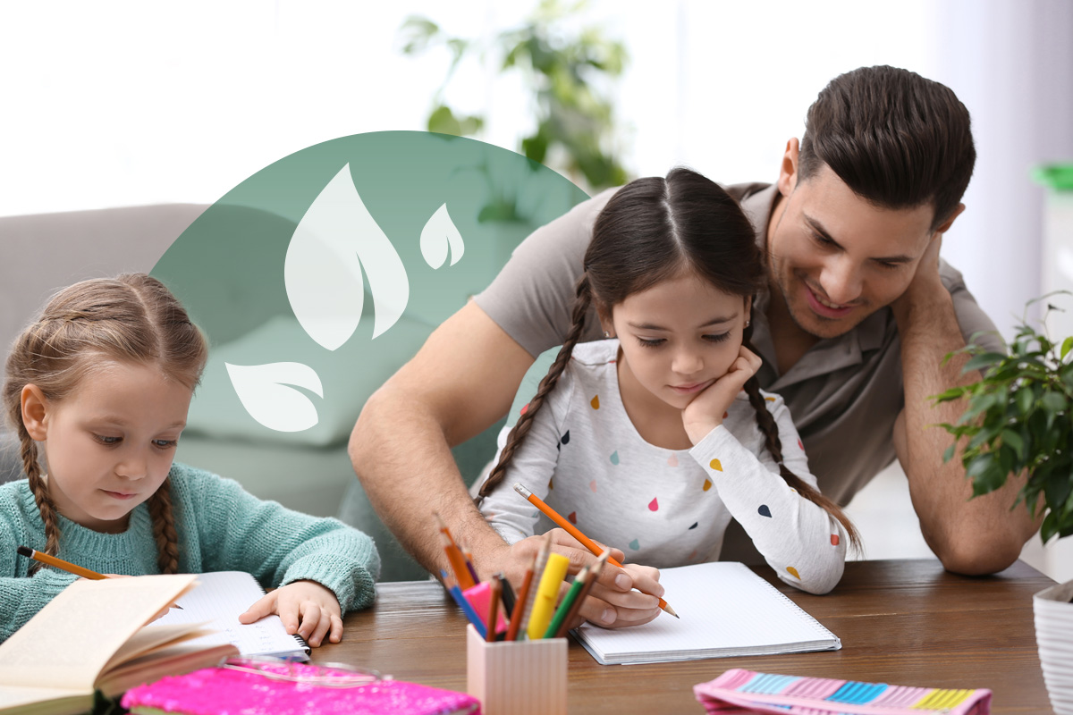 A dad homeschooling his two young daughters at a desk.