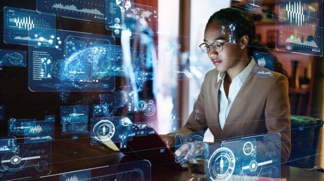 A woman working at a computer which digital computing symbols in a blue hue. 