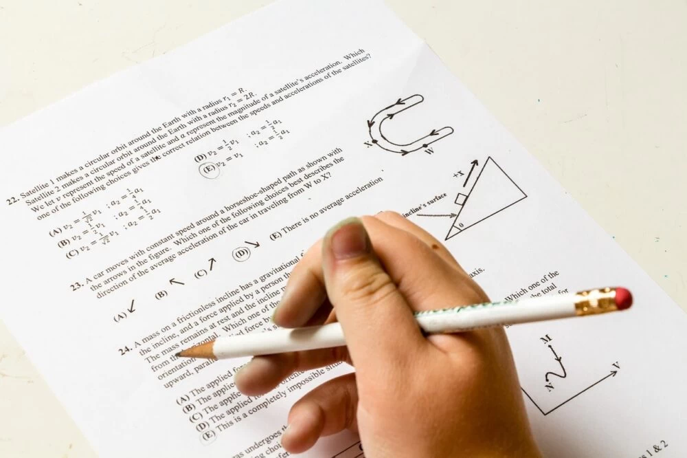 A picture of someone's hand holding a pencil above an exam paper.