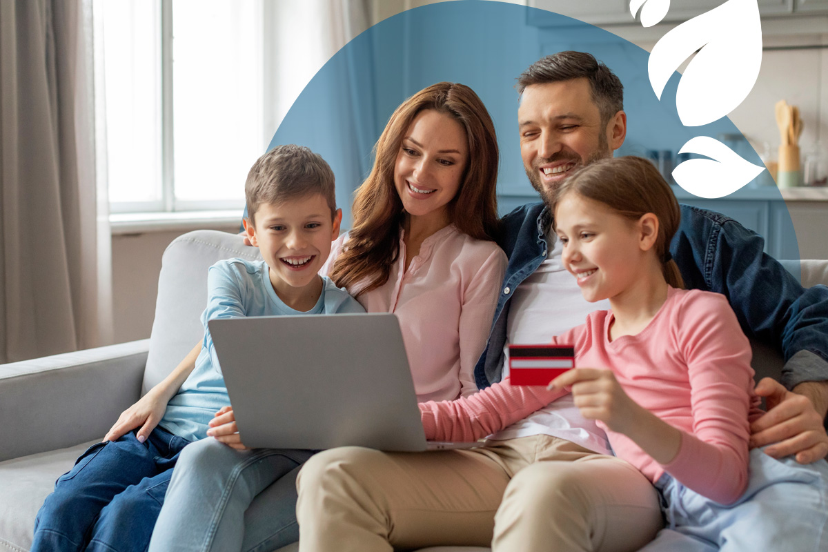 A happy family sitting together on the sofa, enrolling their children in an online school with a laptop.