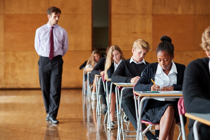 Homeschool students taking formal exams in a UK exam centre with an invigilator present.