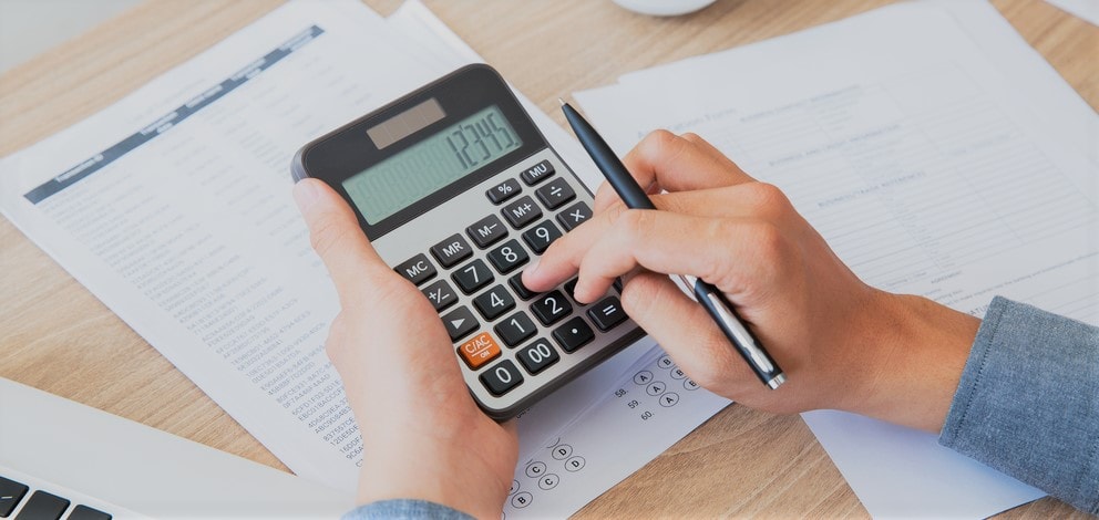 Person calculating figures on a printed statement using a large calculator.