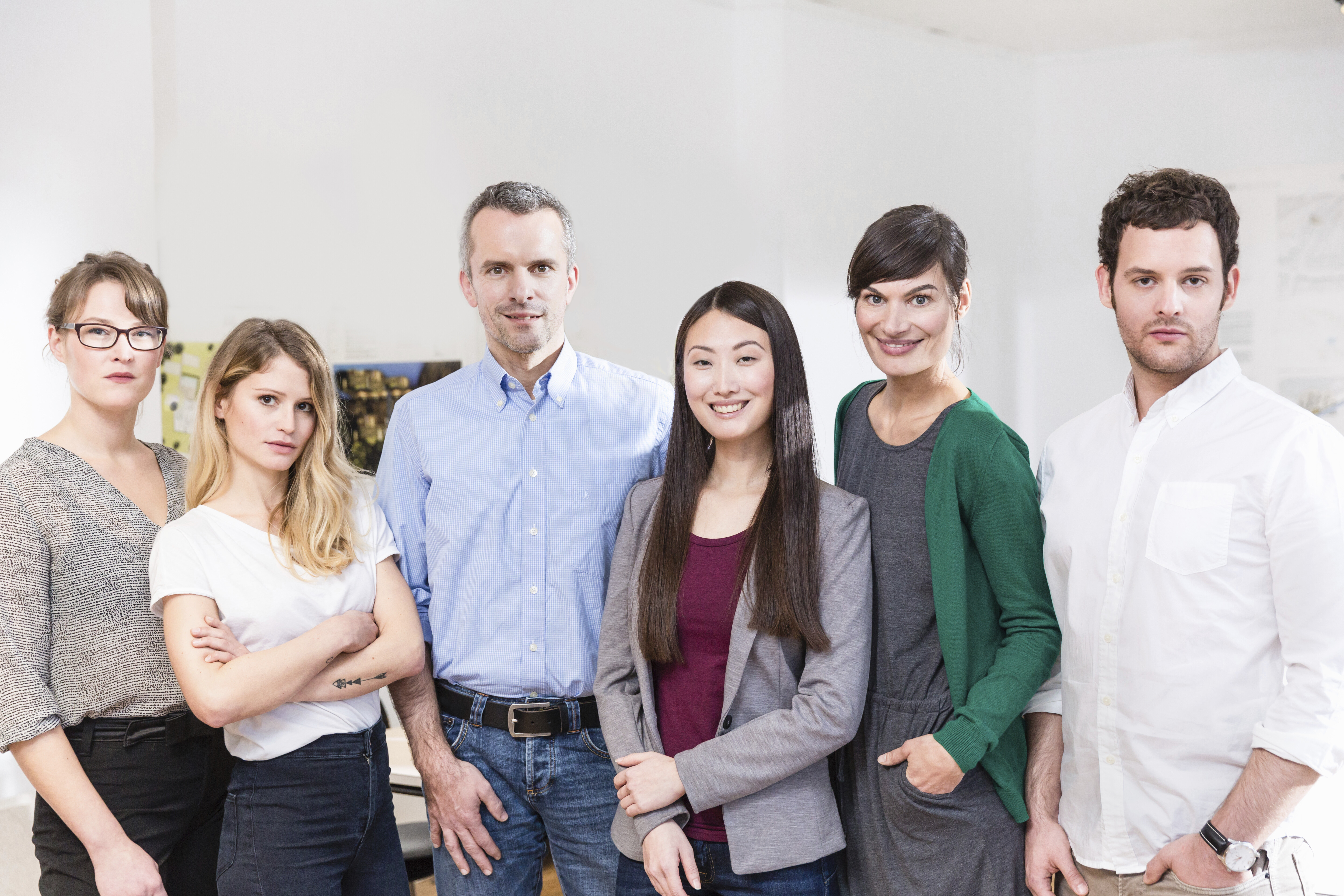 Diverse team of six professionals posing together in a well-lit office space.