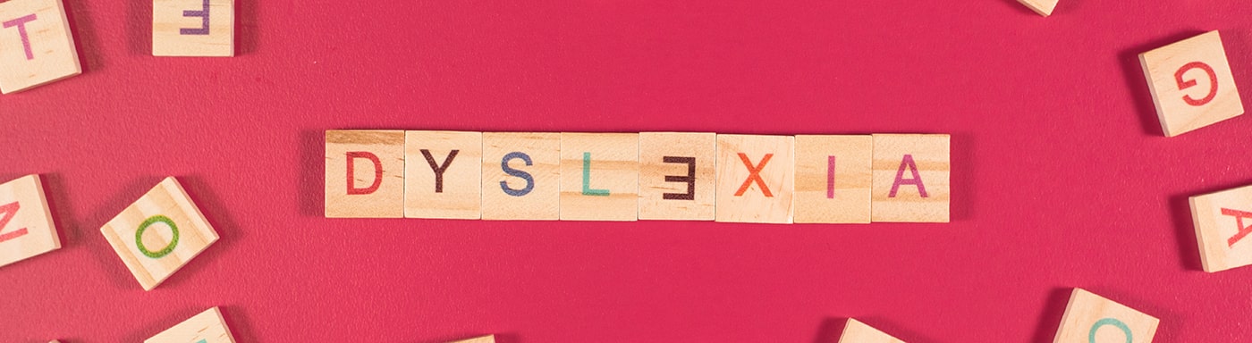 The word 'dyslexia' spelled out using wooden tiles, with the 'E' backwards to highlight the difficulty spelling for people who have dyslexia. 
