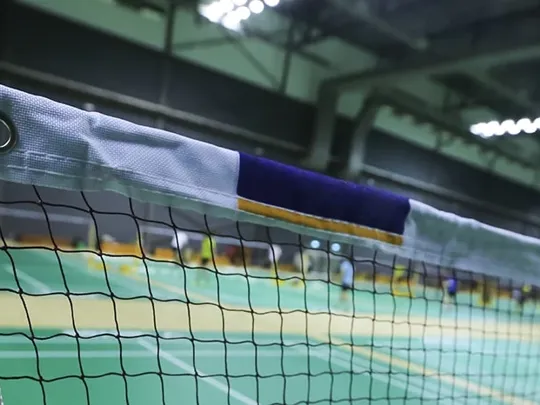 Close up of a badminton net and post on a court in an indoor sports hall.