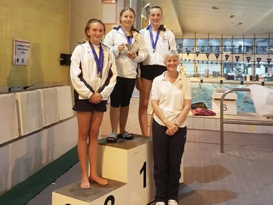WHO student and diver, Olivia, on a medal podium.