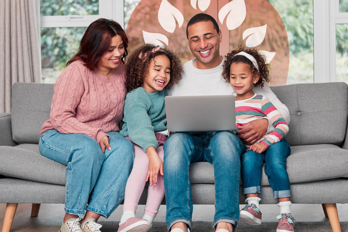 Parents and two young daughters gathered on the sofa enjoying screen time together.