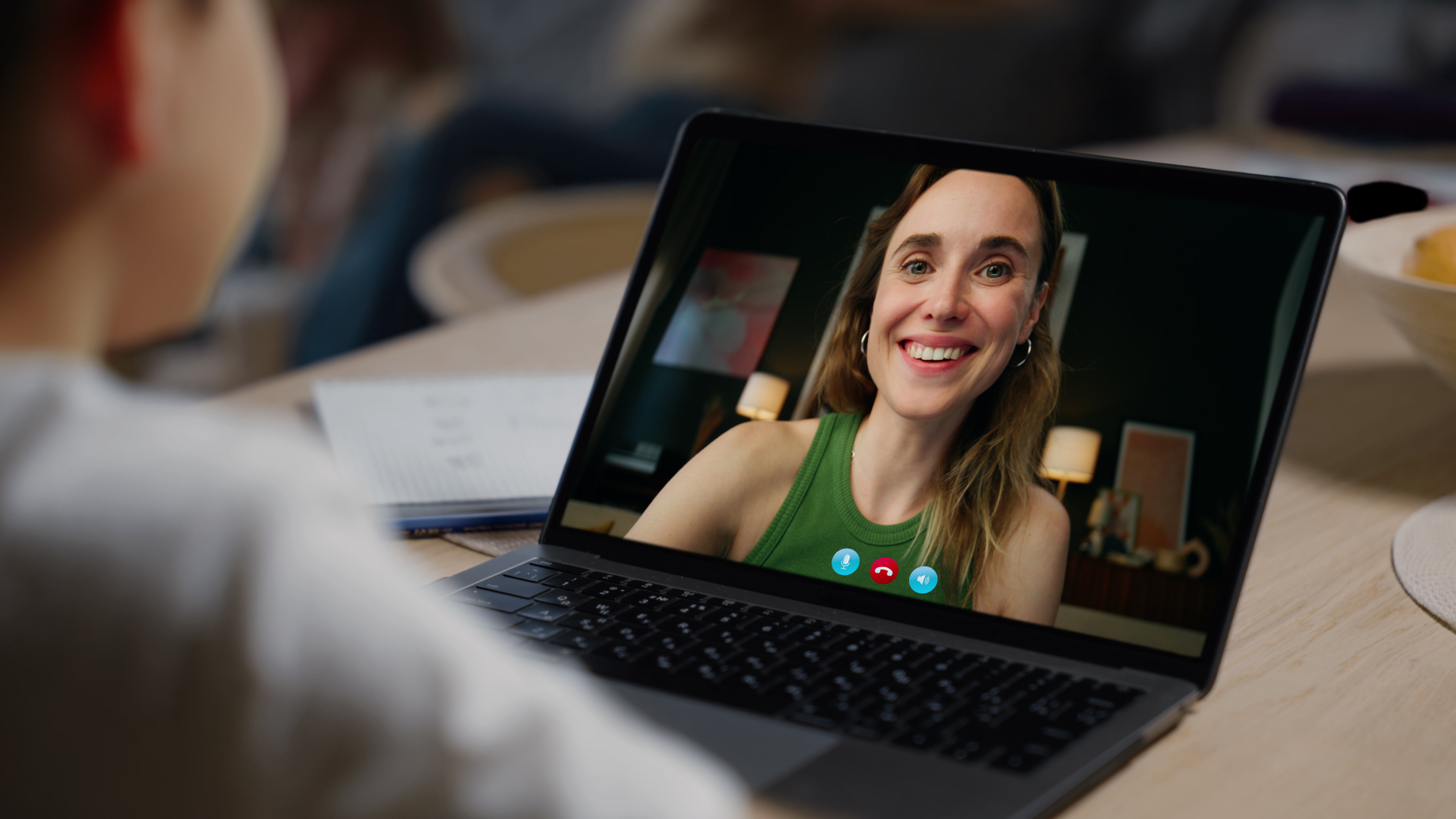 Close-up of a laptop screen showing a smiling tutor on a video call with a student.
