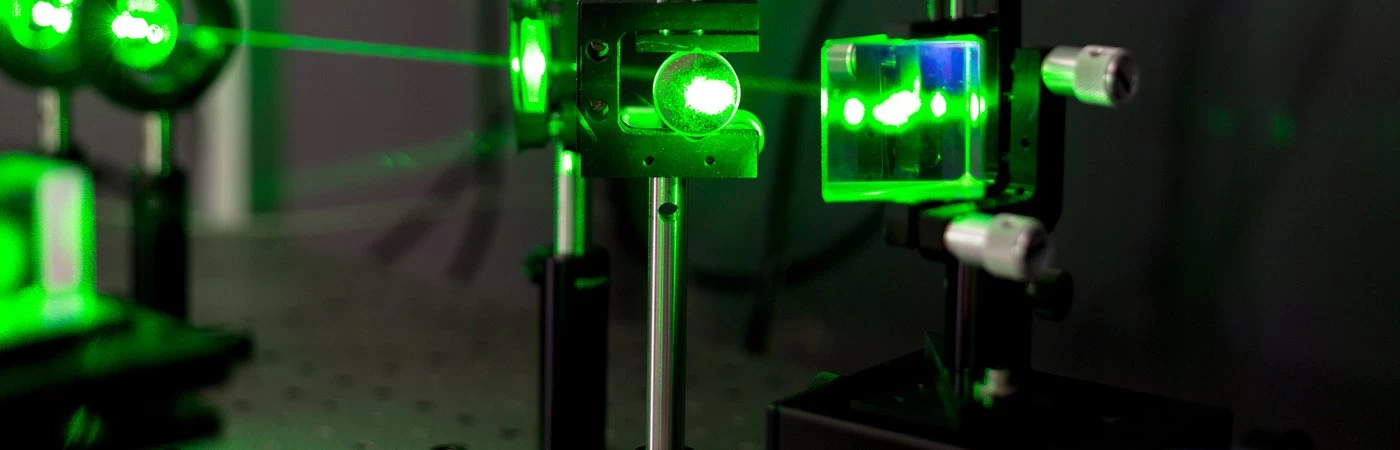 Lasers being shone through a glass prism to test reflection and refraction for a science experiment