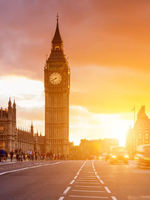 An elapsed photo of a bridge over the River Thames, with Big Ben in the background at sunset.