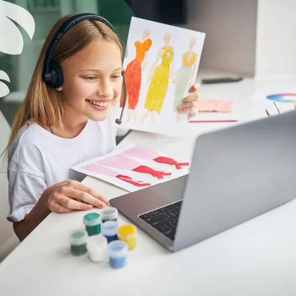 Smiling girl with headset sharing fashion sketches during online art class
