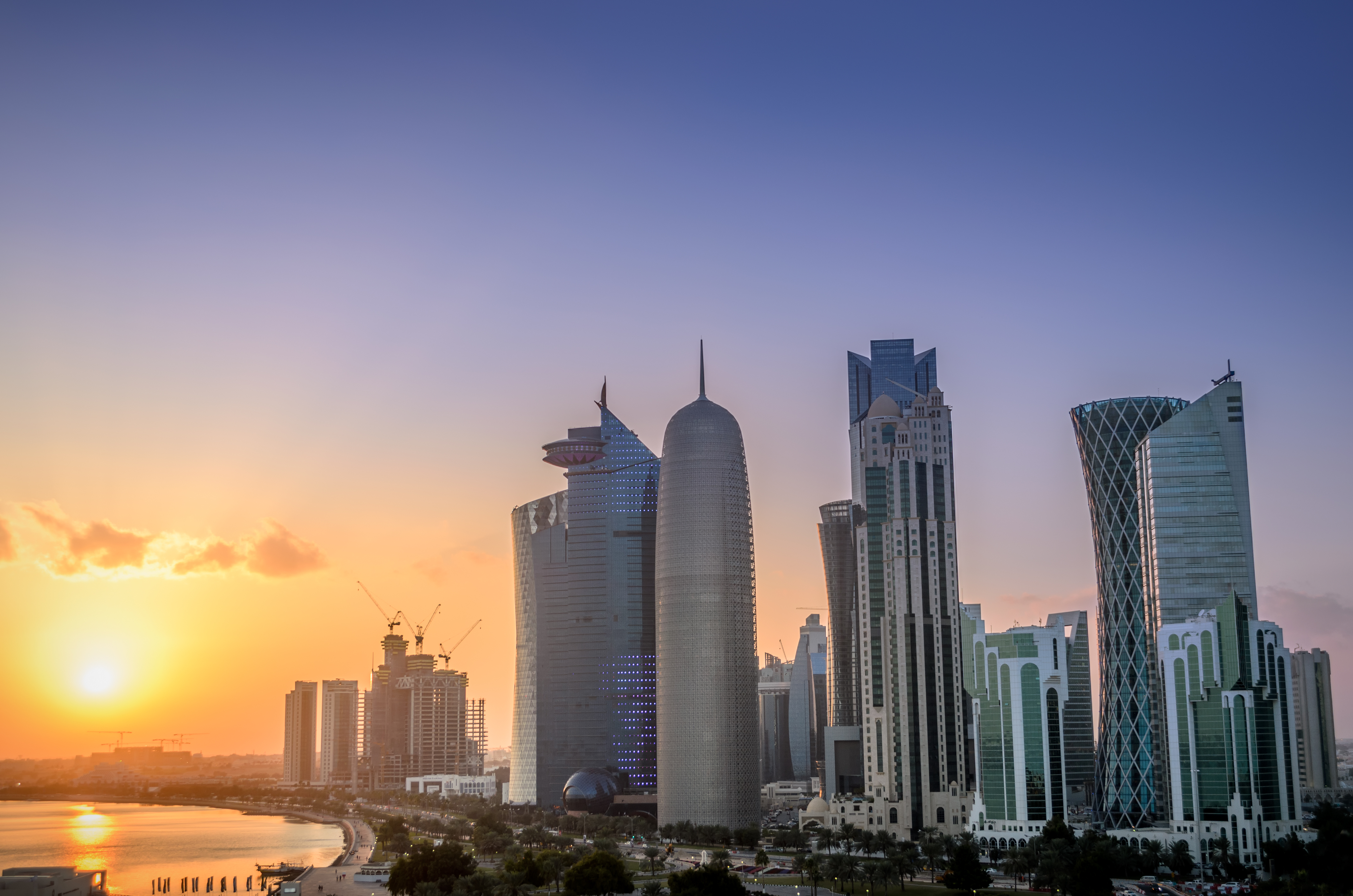 Doha skyline at sunset with iconic modern towers and a golden sky over the bay