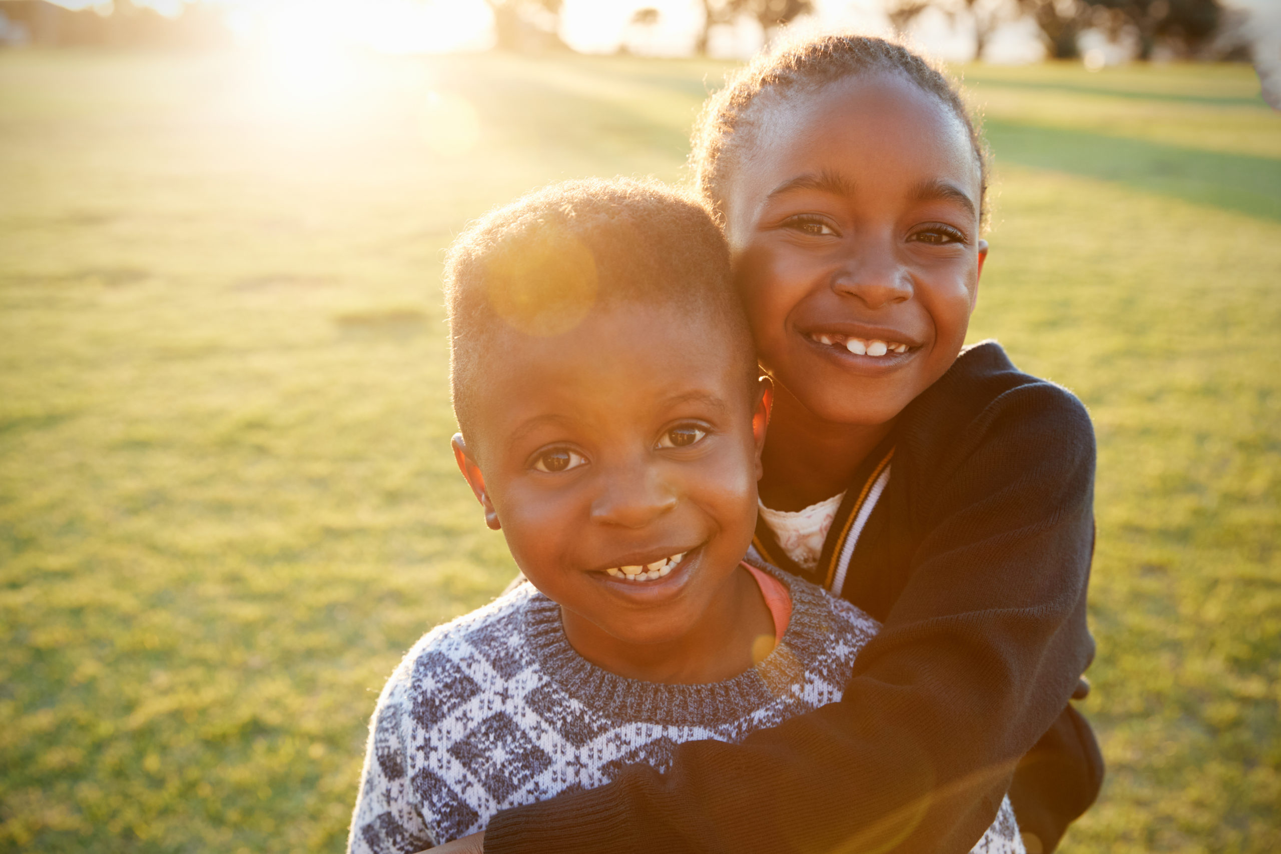 Smiling siblings enjoying a sunny day outside, illustrating the positive social and emotional aspects of homeschooling in Johannesburg.