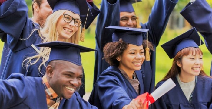 A variety of university students getting ready to graduate wearing gowns and hats. 