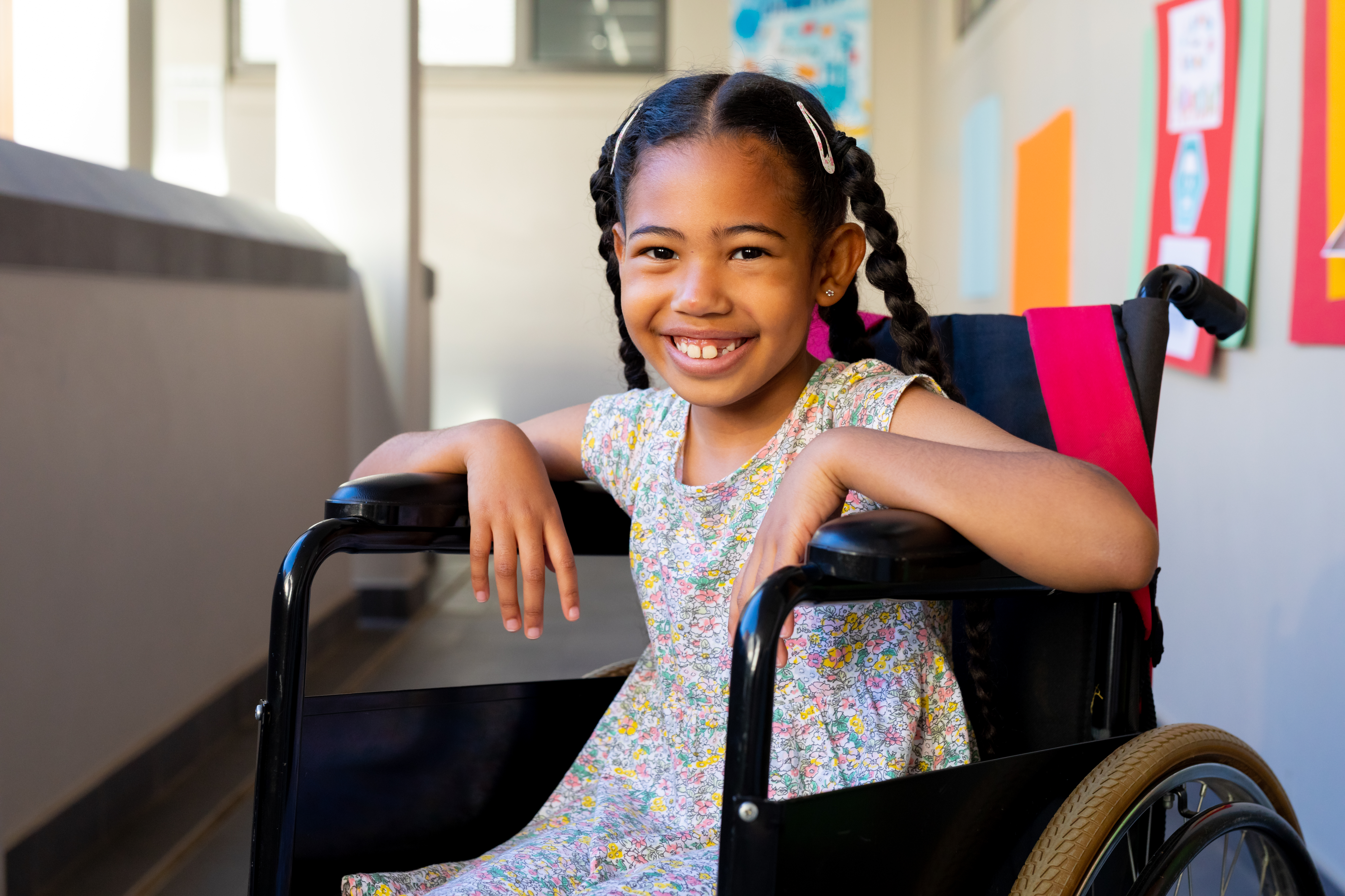 Confident girl smiling in wheelchair in a bright school hallway