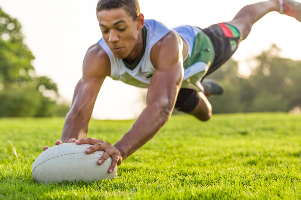 Young male homeschool student in Pretoria diving to score a try in a rugby game, highlighting sports opportunities for homeschoolers.