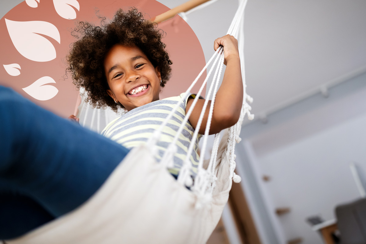 Happy child relaxing in a hammock at home, smiling confidently at the camera.