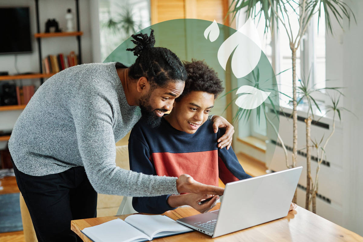 Supportive father helping his son with online learning on a laptop.
