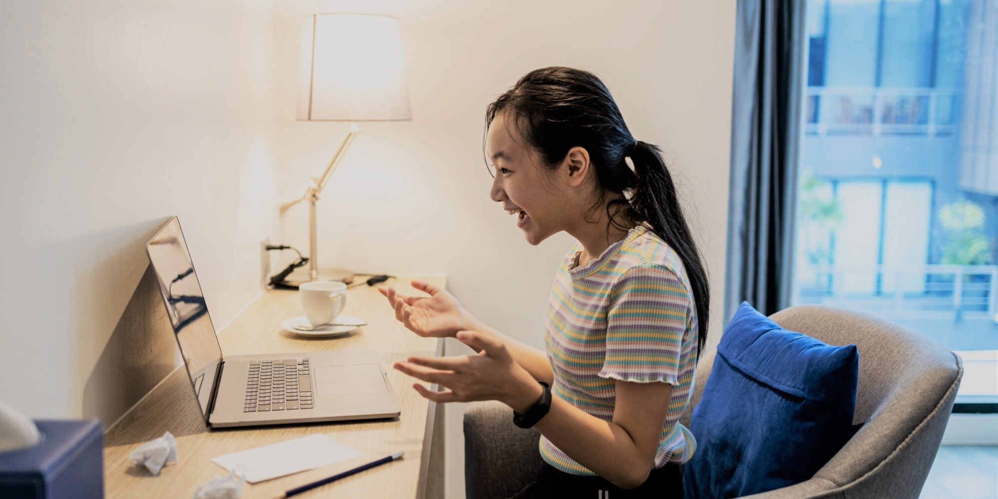 A young girl studying on her laptop at her desk. 