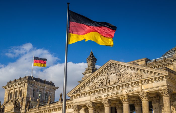 The German flag at full mast infront of an old German building. 