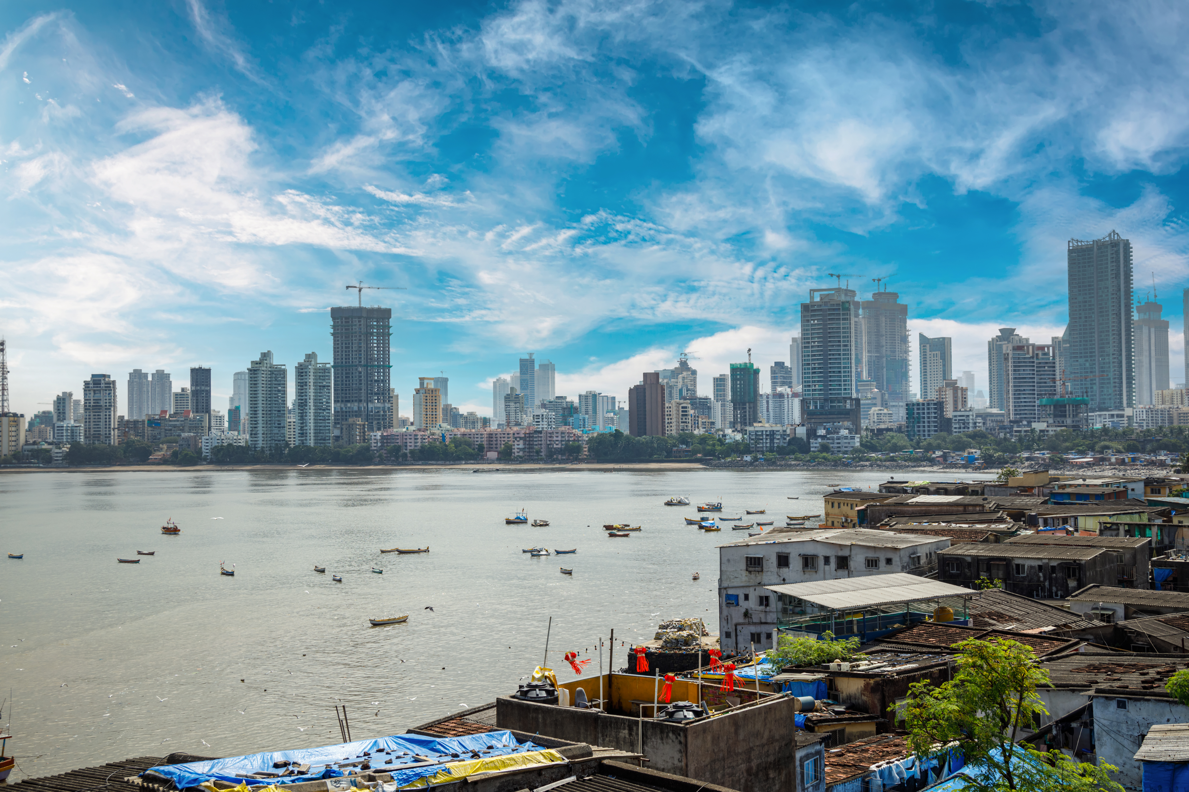 Mumbai skyline with high-rise buildings across the water and small fishing boats in the foreground