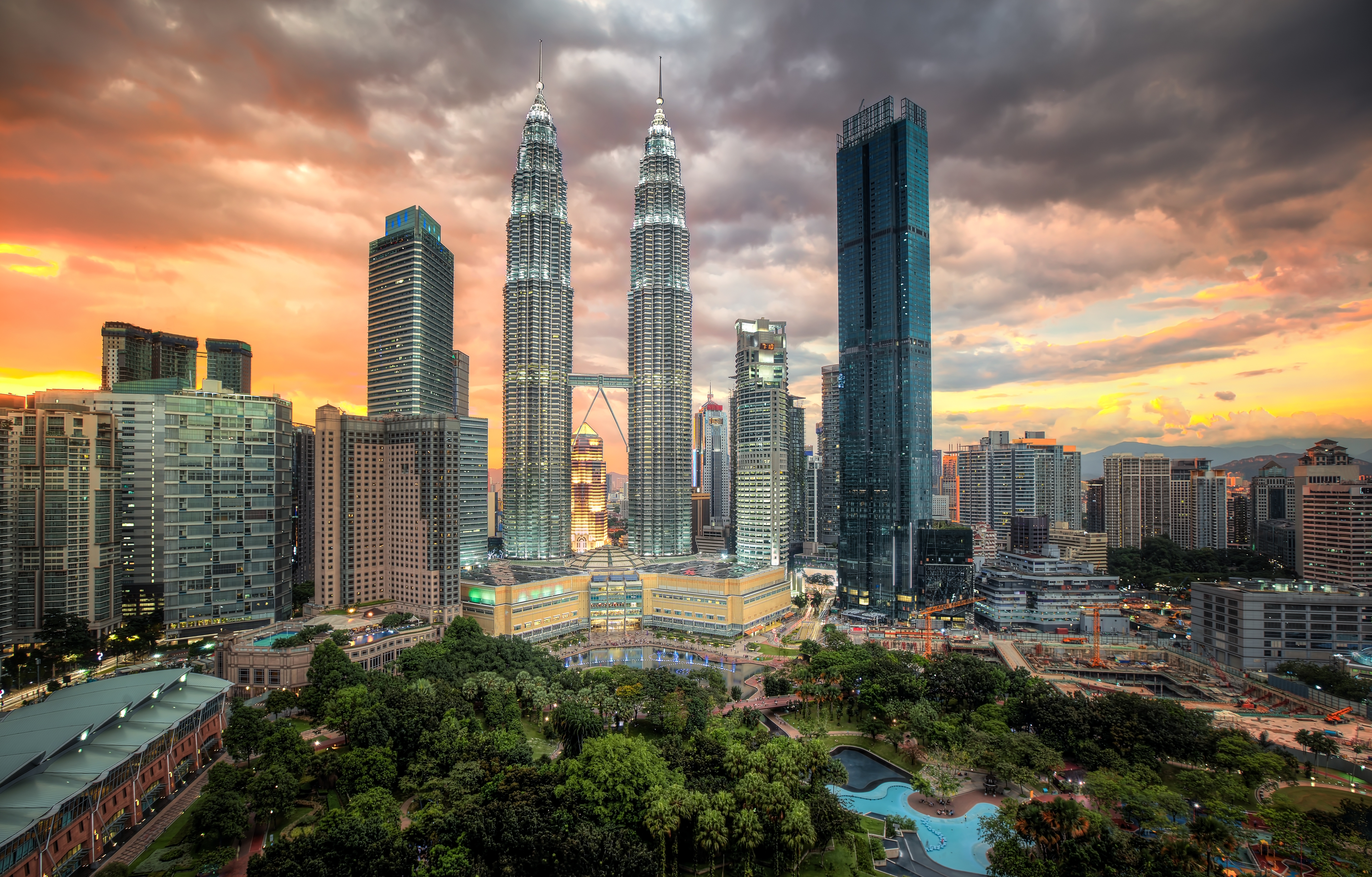 Kuala Lumpur skyline with Petronas Towers at sunset and lush city park in foreground