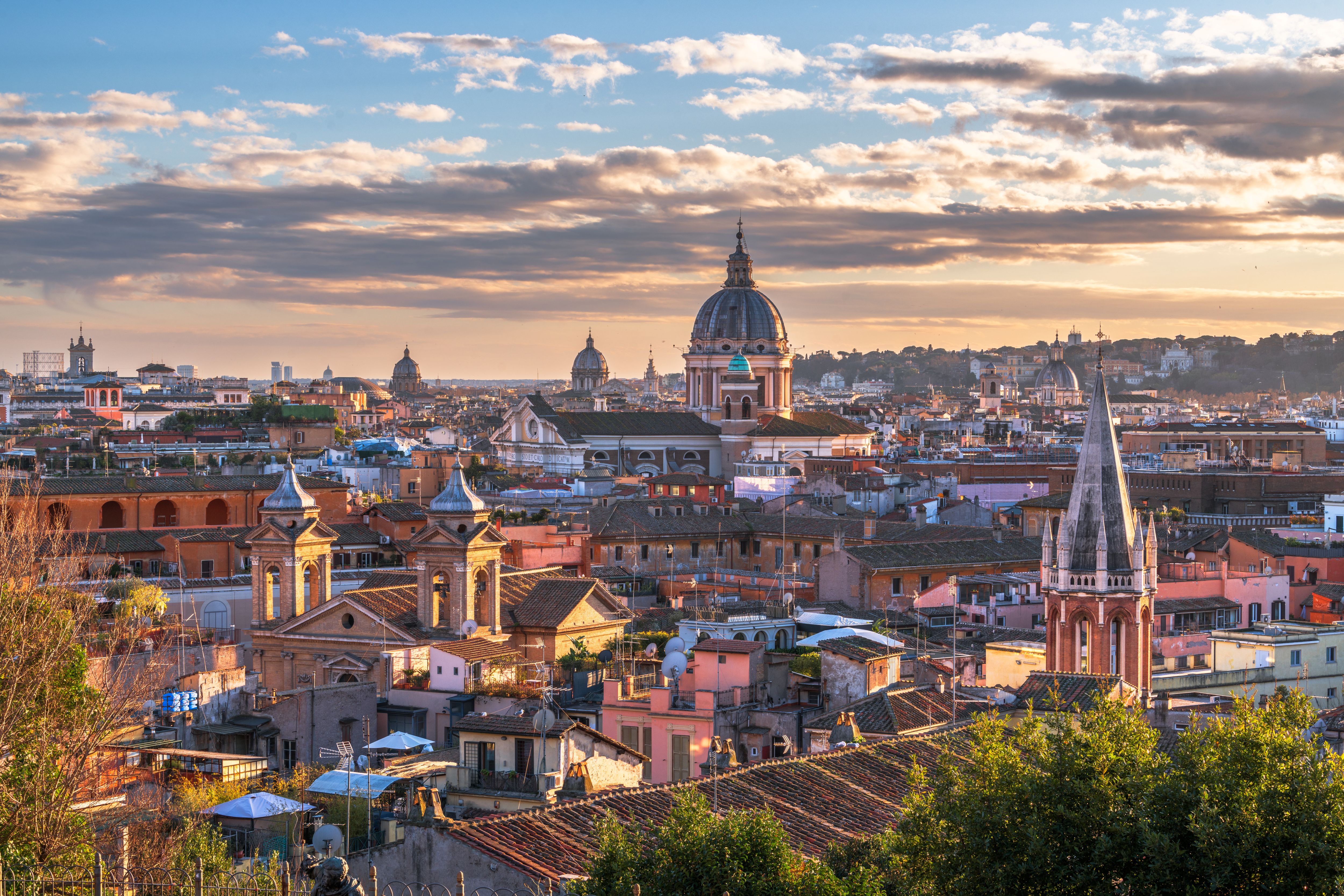 Rome cityscape at sunset with domed churches, terracotta rooftops and spires