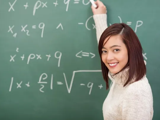 A Teacher writing maths equations on a chalkboard.