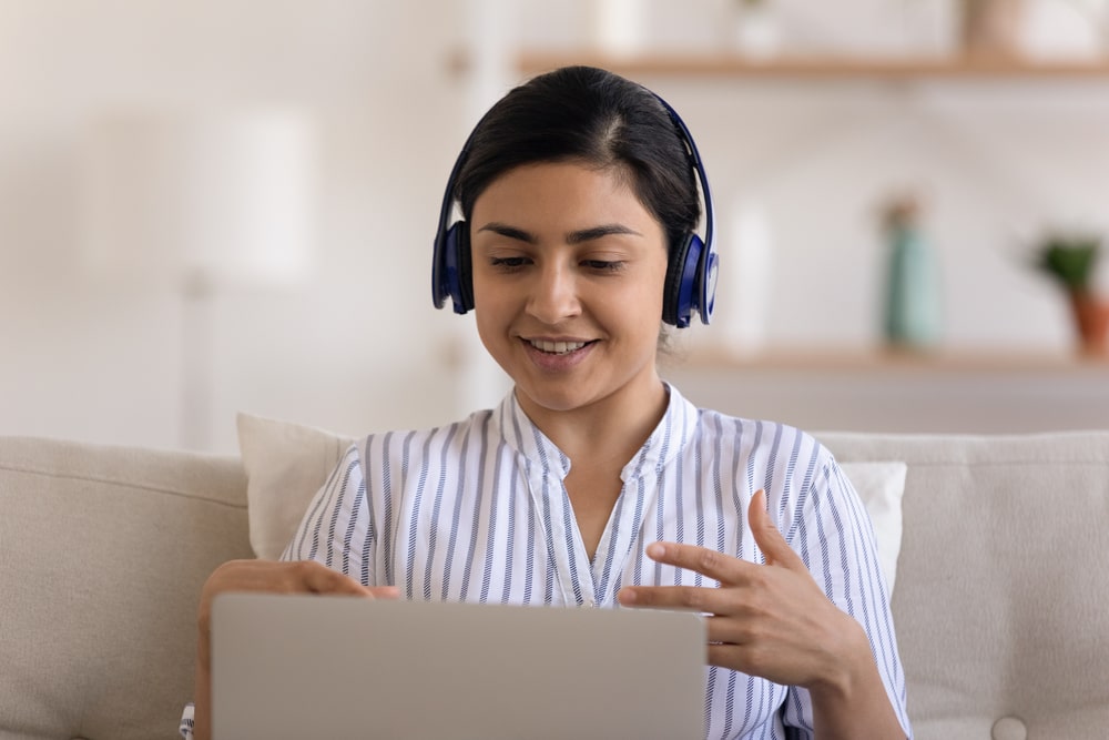Student participating in online tuition session from home in Durban, wearing headphones and engaging with her laptop.